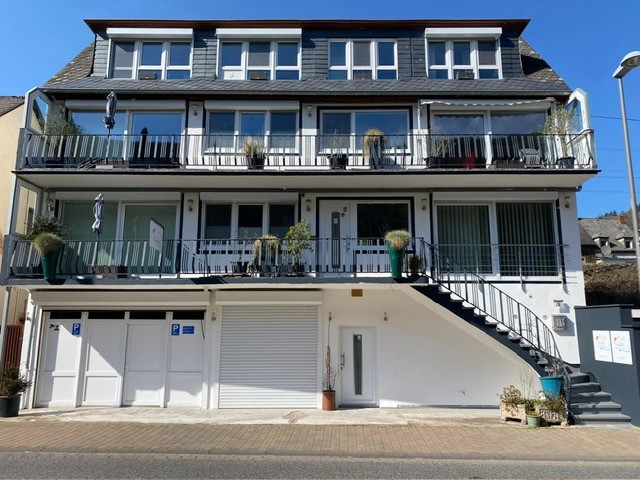 Het wit geschilderde appartementencomplex Moezelzicht in Klotten, met balkons op twee lagen en de garages op straatniveau