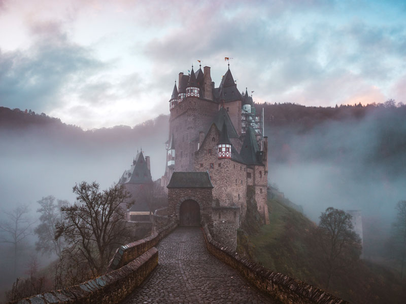 Burg Eltz in de ochtendmist tussen de bomen