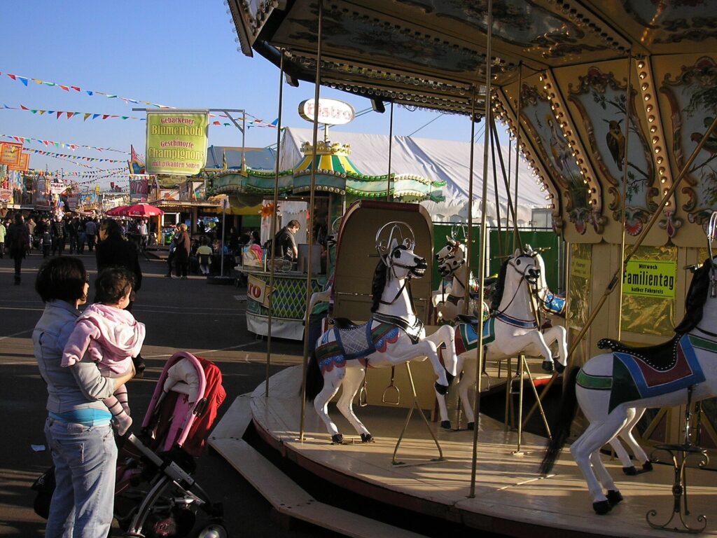 Ouderwetse kermisdraaimolen met houten paardjes op een volksfeest, met vlaggetjes en kraampjes