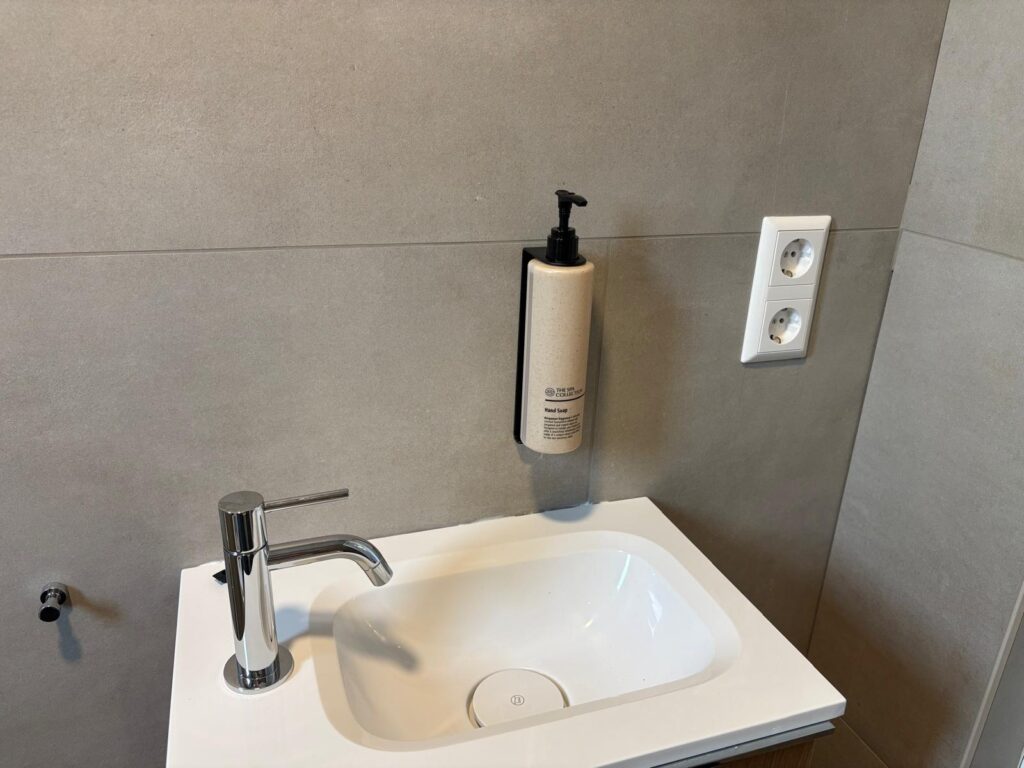 Fonteintje met een pompfles handzeep aan de muur