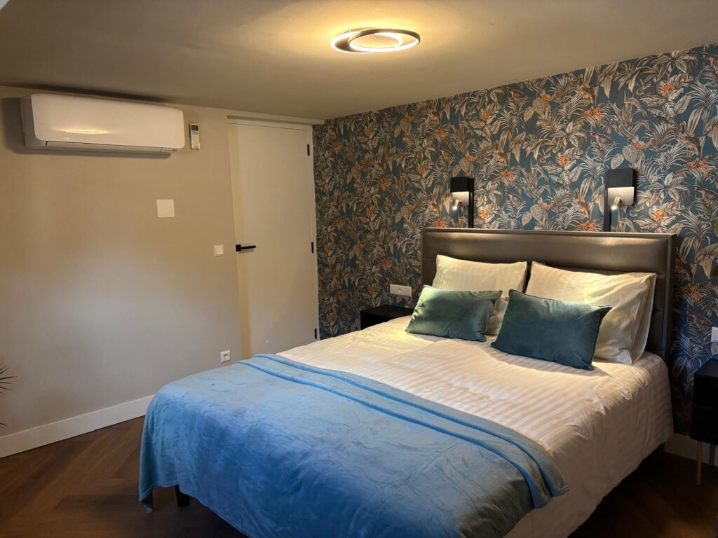 Slaapkamer met tweepersoonsbed, blauw bloemenbehang en een blauwe sprei