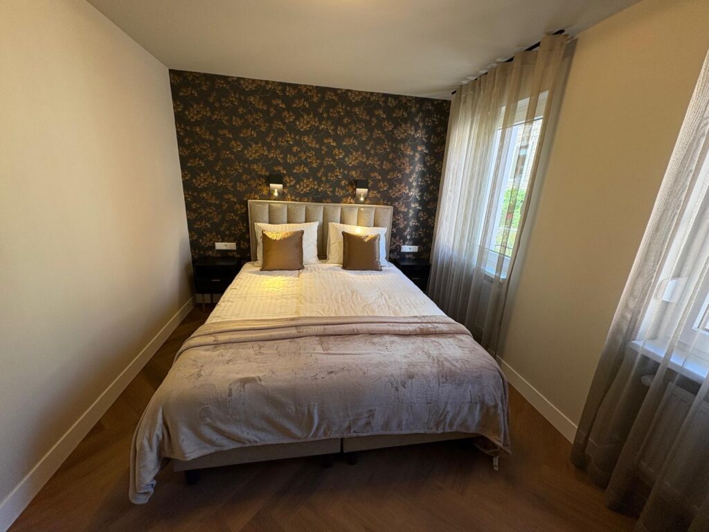 Slaapkamer met tweepersoonsbed en donker bloemenbehang