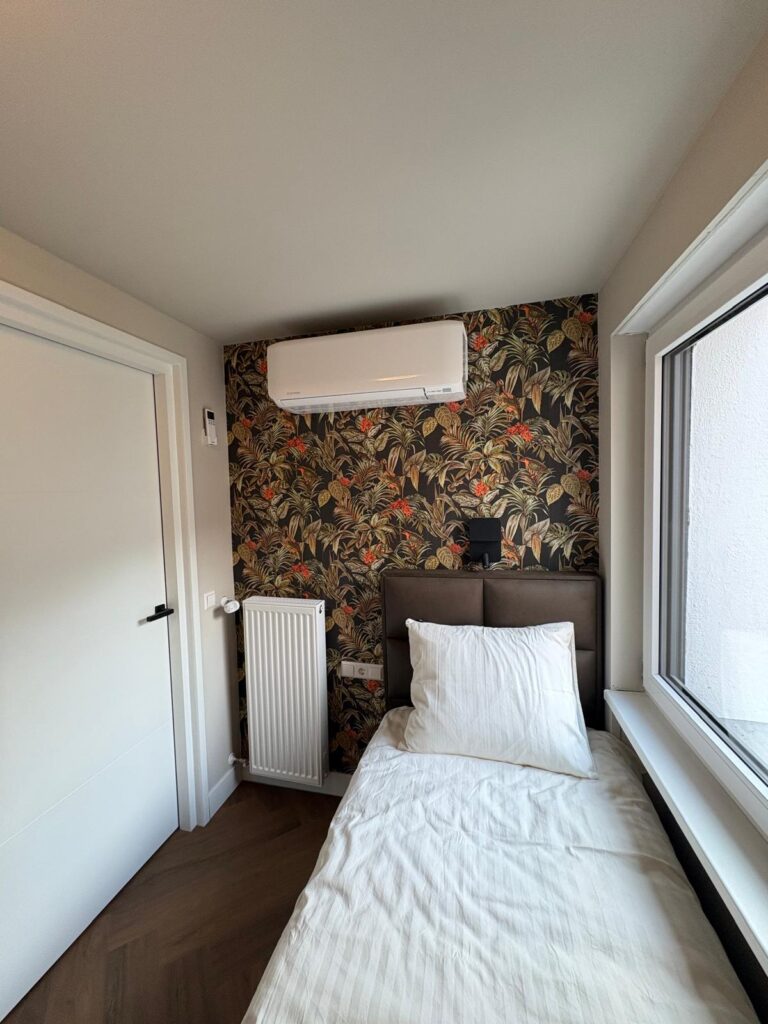 Eenpersoonsbed bij het raam, met airco boven de deur