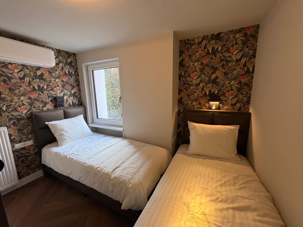 Slaapkamer met twee eenpersoonsbedden en bloemenbehang