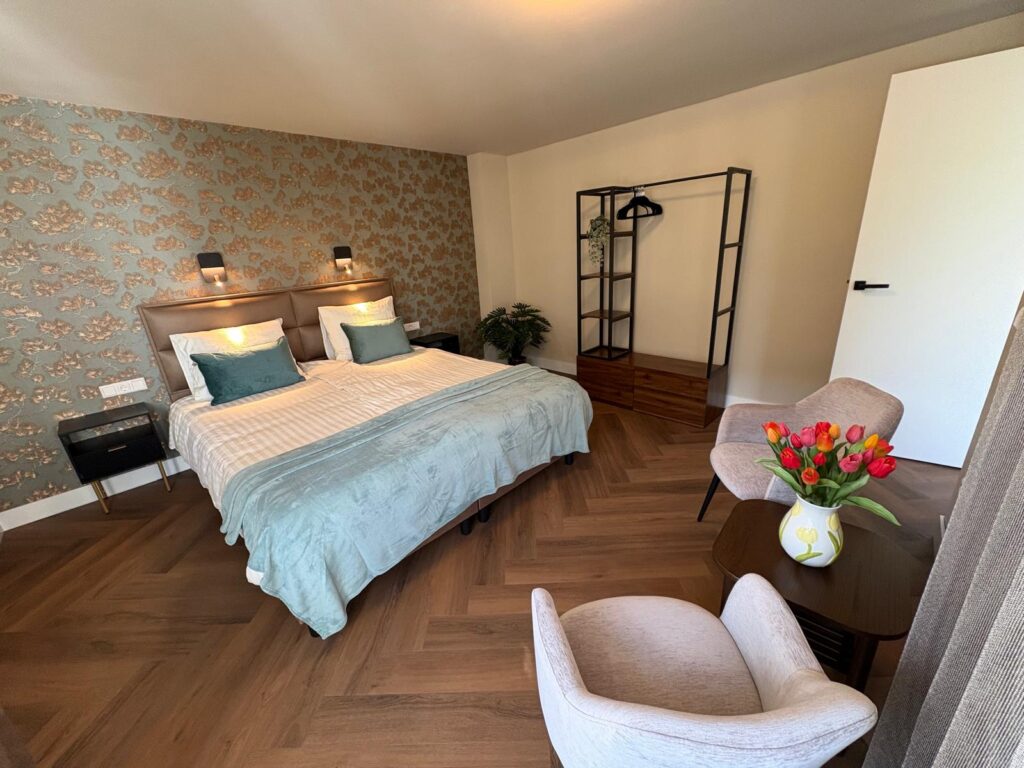 Lichte slaapkamer met tweepersoonsbed en fauteuils bij het raam