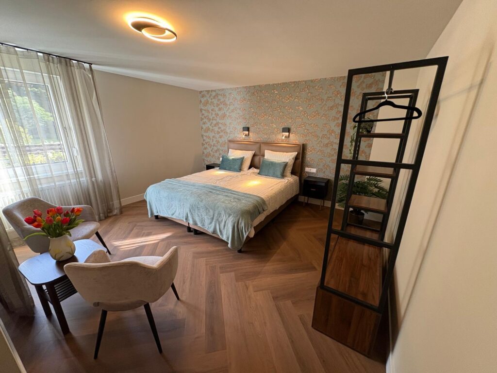 Lichte slaapkamer gezien vanaf de zithoek, met een open kledingrek
