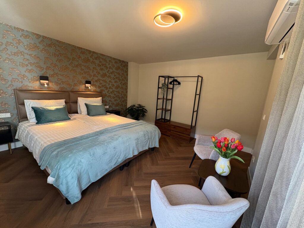 Lichte slaapkamer met tweepersoonsbed, twee fauteuils en tulpen