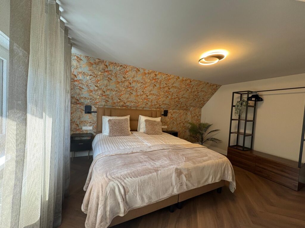 Slaapkamer met oranje bloemenbehang onder het schuine dak