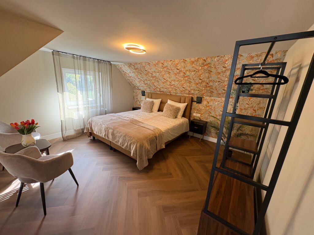 Slaapkamer met oranje bloemenbehang, tweepersoonsbed en twee fauteuils met tulpen