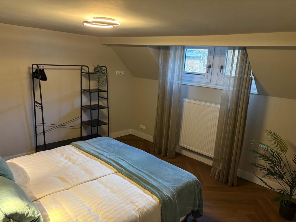 Zolderslaapkamer met tweepersoonsbed en een open kledingrek